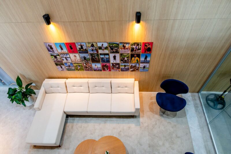 Lounge do evento com sofá branco e painel de fotos de atletas Össur